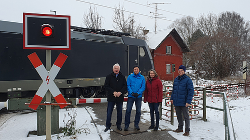 Die vier ÖDP-Aktive stehen vor dem alten Bahnhaltepunkt in Ergolding, als gerade ein Zug einfährt